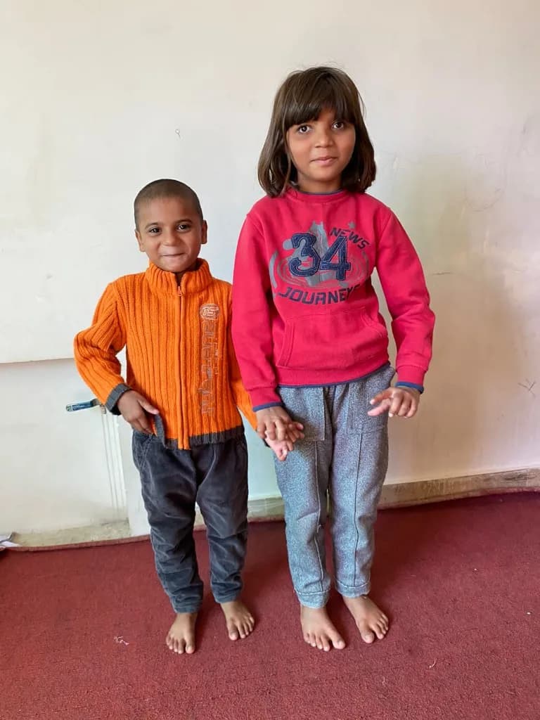 Two children holding hands under Home of Joy care